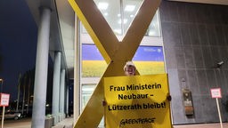 Aktivist hält Schild vor NRW.Ministerium hoch 