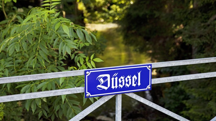 Ein Bild von einem Schild mit dem Schriftzug "Düssel" an einer Flussbrücke