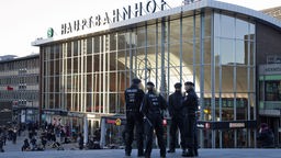 Vier Polizisten stehen vor dem Gebäude des Kölner Hauptbahnhofs