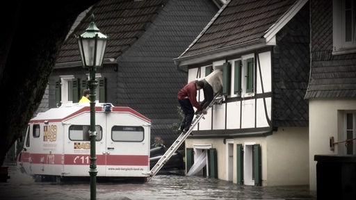Menschen die aus einem Haus gerettet werden mit einer Leiter. 