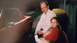 Vater mit seinem Sohn vor einem Porschewagen