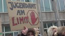 Eine Demonstrierende hält ein Schild mit der Aufschrift "Jugendamt am Limit" hoch.