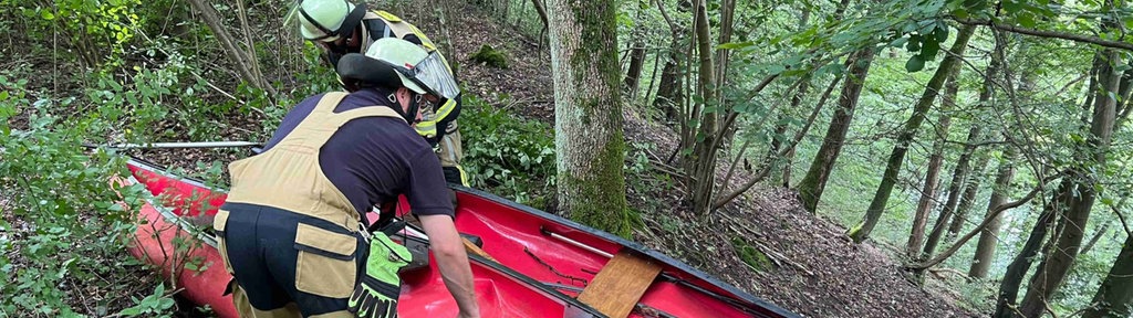 Feuerwehrleute bergen die beschädigten Kanus an einem Steilhang