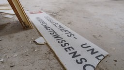 Ein zerbrochenes Schild in den Katakomben der Universität Bonn.