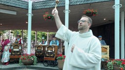Ein Priester segnet die Drehorgeln