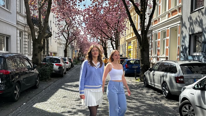 Zwei Frauen gehen unter der blühenden Kirschblüte in Bonn.