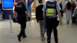 Zwei Polizisten begleiten einen Mann.