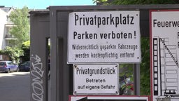 Weißes Schild mit der Aufschrift: Privatparkplatz parken verboten!
