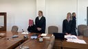 Der Angeklagte verdeckt mit einer Mappe im Gerichtssaal sein Gesicht
