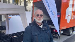Rastherr Ralf Krings von den Freien Wählern steht vor dem mit Lebensmitteln gefüllten LKW