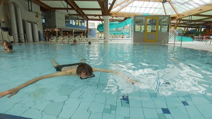 Ein Mann schwimmt bäuchlings und mit dem Gesicht unter Wasser in einem Schwimmbecken.