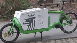 Grünes Fahrrad mit weißer, daran montierter Box
