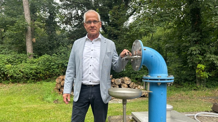 Langenfelds Bürgermeister Frank Schneider steht neben einem Wasserrohr.