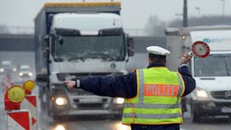 Ein Polizist winkt an der Leverkusener Autobahnbrücke einen Lastwagen an die Seite. 
