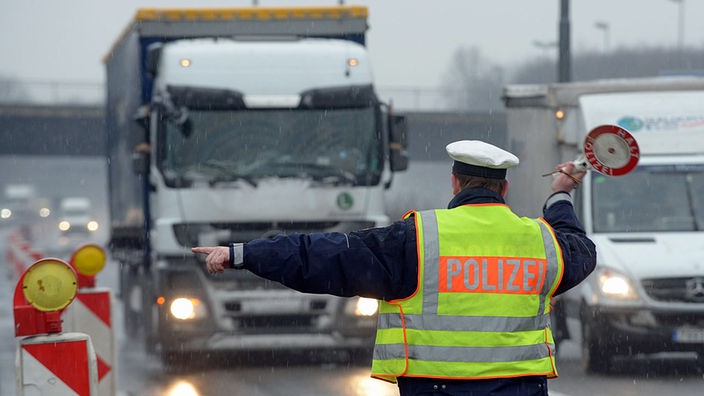 Ein Polizist winkt an der Leverkusener Autobahnbrücke einen Lastwagen an die Seite. 