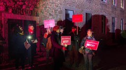 Menschen mit Lichtern und Plakaten auf dem abendlichen Domhof