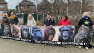 Tierschützer halten Plakate mit den Porträts der getöteten Affen