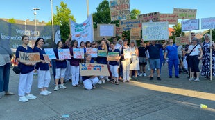 Mehrere Demonstrierende halten Plakate hoch mit Texten wie "Wir retten Leben" und "Wer rettet uns?" 