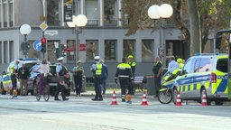 Mehrere Polizisten stehen mit zwei Streifenwagen am Rande einer Straße und kontrollieren