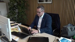 Bürgermeister Sascha Solbach sitzt vor einem Laptop und tippt etwas auf der Tastatur.