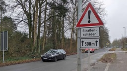 Straßenschild mit Warnhinweis vor Straßenschäden