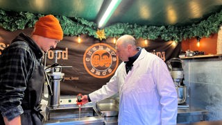 Lebensmittelkontrolleur prüft die Temperatur von Fritierfett an einer Bude auf dem Weihnachtsmarkt.