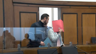 Die Angeklagte hält sich einen roten Hefter vor das Gesicht