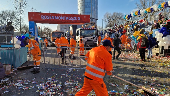 Müllmänner der Kölner Abfallwirtschaftsbetriebe machen am Rosenmontagszug die Straßen sauber