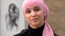 Porträtbild von Basmala Ashqar mit schwarzem Pulli und rosa Kopftuch