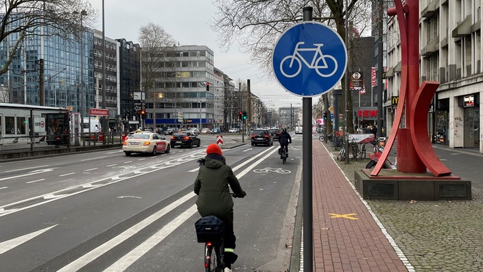 Fahrradfahrerin fährt auf neuem Radweg auf der Straße in Köln