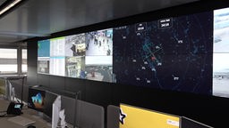 Das Bild zeigt mehrere Monitore im neuen Kontrollzentrum. Sie zeigen Bilder vom Flughafen an oder Flugzeug-Positionen.