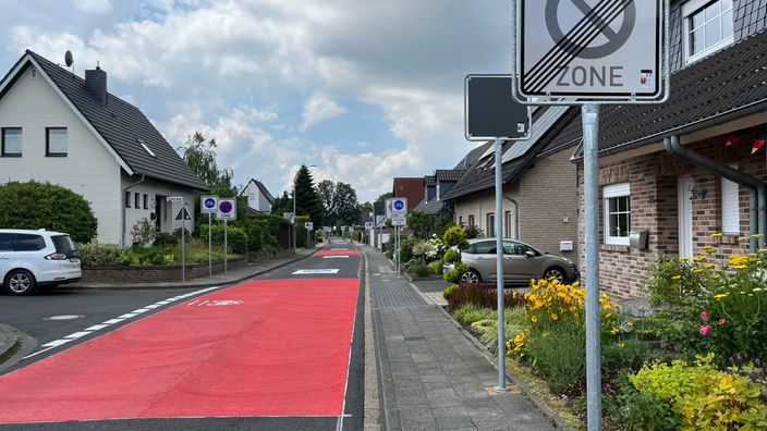 Eine rot markierte Fahrradstraße mit Straßenschildern auf beiden Seiten 