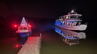 Zwei Schiffe auf einem See im Dunkeln, an Bord mit bunten Lampen beleuchtet