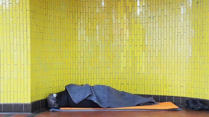 Ein obdachloser Mann liegt in einem Bahnhof (Symbolfoto)