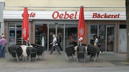 Fassade einer Bäckerei, davor gehen Fußgänger