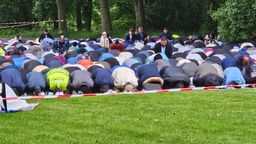 Gläubige Muslime knien und beten unter freiem Himmel