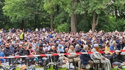 Mehrere tausend Gläubige sitzen auf  einer Wiese auf der Hardt in Wuppertal