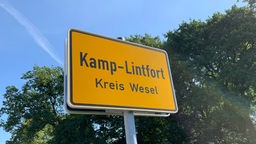 Gelbes Ortsschild mit Schriftzug "Kamp-Lintfort" des Kreises Wesel