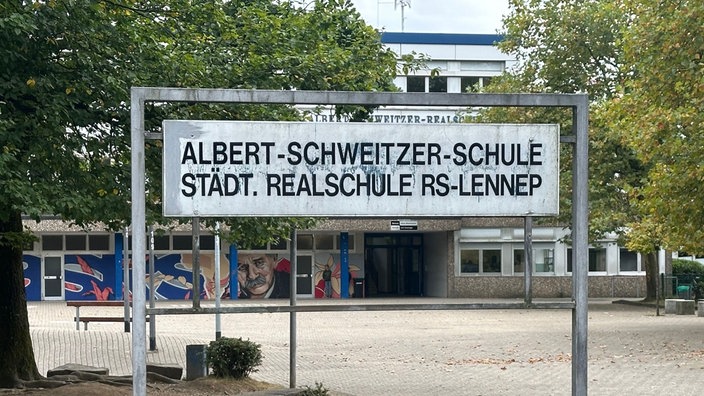 Ein Schild mit der Aufschrift "Albert-Schweitzer-Schule - städt. Realschule RS-Lennep", im Hintergrund die Schule