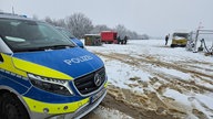 Ein Polizeiwagen steht vor einer schneebedeckten Fläche in Nähe des Hambacher Forstes.