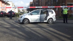 Das Foto zeigt ein silbernen VW Touran und ein rot-weißes Flatterband der Polizei