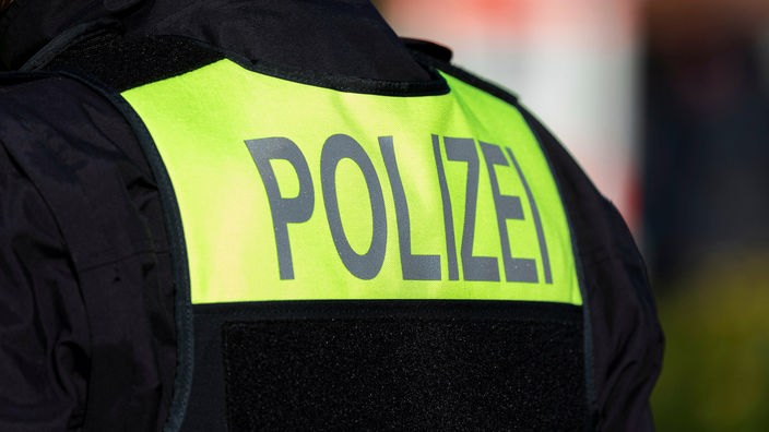 Symbolfoto: Der Schriftzug "Polizei" auf dem Rücken eines Polizisten.