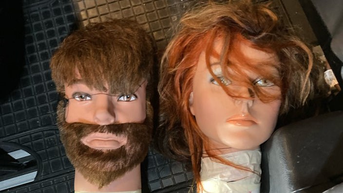 zwei Puppenköpfe, einer mit langen Haaren, einer mit Bart 
