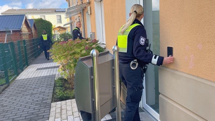 Polizist*innen klingeln an die Haustüren der Bewohner.