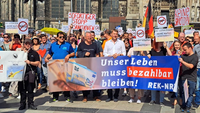Vor dem Kölner Dom stehen rechtsradikale Gruppen, die das Ende der Sanktionen gegen Russland fordern