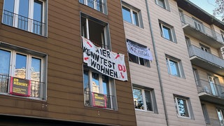 Porotestbanner mit der Aufschrift "Hier könntest du wohnen" an einer Hauswand