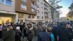 Protestgruppe vor einem Gebäude an dem ein Banner hängt "Hier könntest du wohnen"