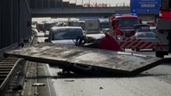 Eine Betonplatte liegt auf einem zerstörten Kleinwagen auf der A3, während Einsatzkräfte und Feuerwehr die Unfallstelle absichern.