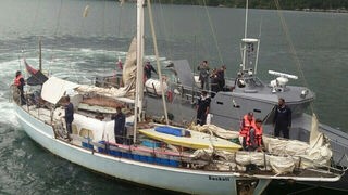 Ein graues Motorboot ist an einem Segelboot gedockt