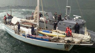 Ein graues Motorboot ist an einem Segelboot gedockt